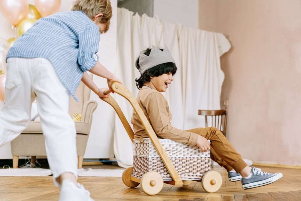 child doing heavy work by pushing his friend in a cart